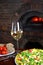 Tasty pizza and glass with red wine in a traditional restaurant with a fire stone stove.