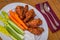 Tasty plate of glazed chicken wings with carrots, celery and dipping sauce.