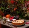 Tasty plum cake on vintage plate on brown rustic table with plates, cup, basket with plums