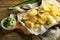 Tasty potato chips with sour cream and herbs on wooden background