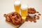 Tasty pretzels, crackers and glasses of beer on white wooden table