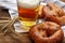 Tasty pretzels, glass of beer and wheat spikes on wooden table, closeup