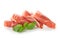 Tasty prosciutto slices with basil on white background