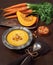 Tasty pumpkin and carrot cream soup served with croutons and pumpkin seeds in metal pewter bowl