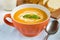 Tasty pumpkin soup with cream in orange bowl.