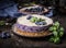 Tasty purple blueberry no bake cheesecake decorated with fresh blueberries and mint leaves on dark rustic background. side view