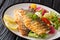 Tasty recipe for spicy grilled sea bass fillet with lemon and vegetable salad close-up on a plate. horizontal