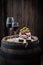 Tasty red wine in glass with olives and cold meats on wooden barrel