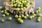 Tasty ripe gooseberries, wooden tray on the grey rural surface