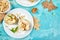 Tasty roast pears with honey and walnuts on white plates on blue background table.