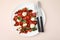 Tasty salad Caprese with tomatoes, mozzarella balls, basil and cutlery on beige background, top view
