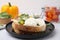 Tasty sandwich with burrata cheese and vegetables on white table, closeup