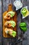 Tasty sandwiches - toasted bread with cream cheese, smoked salmon, avocado and parsley on wooden table, top view