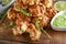 Tasty sausage balls and bowl with sauce on wooden board, closeup