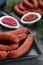 Tasty sausages served on black table, closeup. Meat product