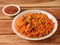 Tasty schezwan chicken fried rice with tomato sauce served in white bowl over a rustic wooden background, Indian cuisine,