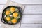 Tasty Shakshouka in frying pan on white wooden table, top view. Space for text