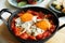 Tasty Shakshouka served in pan on table