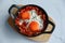 Tasty Shakshouka served in pan on white marble table, top view