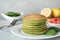 Tasty spinach pancakes on light grey table, closeup