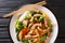 Tasty Stir fry mix of vegetables, chicken and tofu close-up in a plate. Horizontal top view