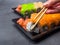 Tasty sushi bar, Eating Sushi with chopsticks. California Sushi roll set with salmon, vegetables, fish, caviar closeup. Japan