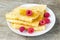 Tasty sweet thin pancakes with fresh raspberries and honey on plate, delicious dessert, closeup, wooden background
