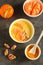 Tasty tangerine smoothie bowl with fruits, cereals, seeds and turmeric powder over grey background