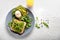 Tasty toasts with avocado and egg Benedict on plate