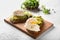 Tasty toasts with avocado and eggs Benedict on wooden board