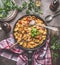 Tasty tortellini pasta pot with vegetables sauce and spoons on rustic kitchen table background with plates and cutlery, top view.