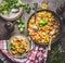 Tasty tortellini pot with vegetables sauce served on plate with spoons and greens on rustic kitchen table background, top view. He