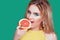 Tasty tropical fruits! Attractive sexual woman with beautiful makeup and wet hair eating fresh juicy grapefruit or orange smiling