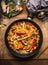 Tasty vegetarian fried noodles pan with vegetables and creamy pasta sauce on wooden background