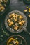 Tasty vegetarian tortellini with creamy vegetables sauce in plate with fork on dark rustic table background with vegetables