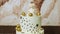 A tasty white cake decorated with golden stars and balls with figure of a angel