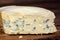 Tasty whole blue cheese with mold on wooden background, close up