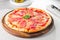 Tasty whole Italian pizza topped with thinly sliced prosciutto ham