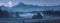 the Tatras veiled in haze, framed by dense forest and rural fields under the shimmering glow of a full moonlit night