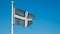 Tattered Devon county flag flies against a blue sky near Teignmouth Beach in Devon, UK