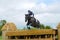 Tattersalls horse show in Ireland, black horse jumping over obstacle with male rider, jockey