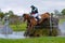 Tattersalls horse show in Ireland, chestnut horse jumping over obstacle in water with male rider, jockey rushing forward