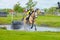 Tattersalls horse show in Ireland, horse after obstacle in water with female rider, jockey rushing forward