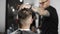 Tattoed barber makes haircut for customer at the barber shop, man`s haircut and shaving at the hairdresser, barber