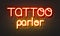Tattoo parlor neon sign on brick wall background.