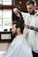 tattooed hairdresser drying hair of brunette