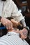 tattooed hairdresser shaving neck of bearded