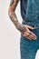 A tattooed hand lying over a denim overall of a white woman