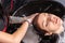 Tattooed hands of the hairdresser wash the hair of a young client with dyed hair