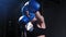 Tattooed woman in protective soft helmet and boxer gloves training fighting in the gym